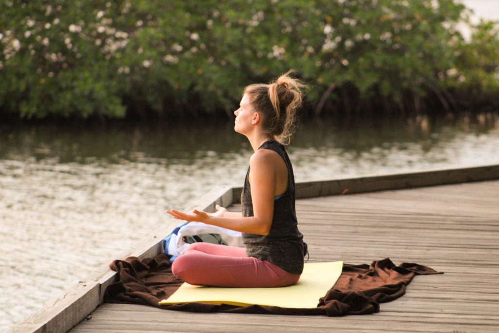 Woman doing yoga on dock with pink pants